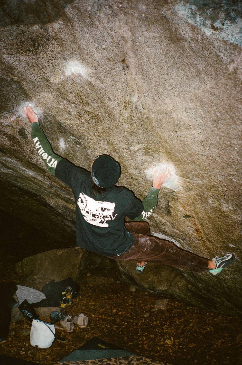 Person climbing a rock wall with visible branding on clothing
