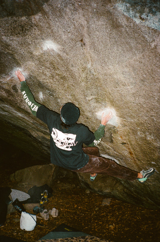 Person climbing a rock wall with visible branding on clothing